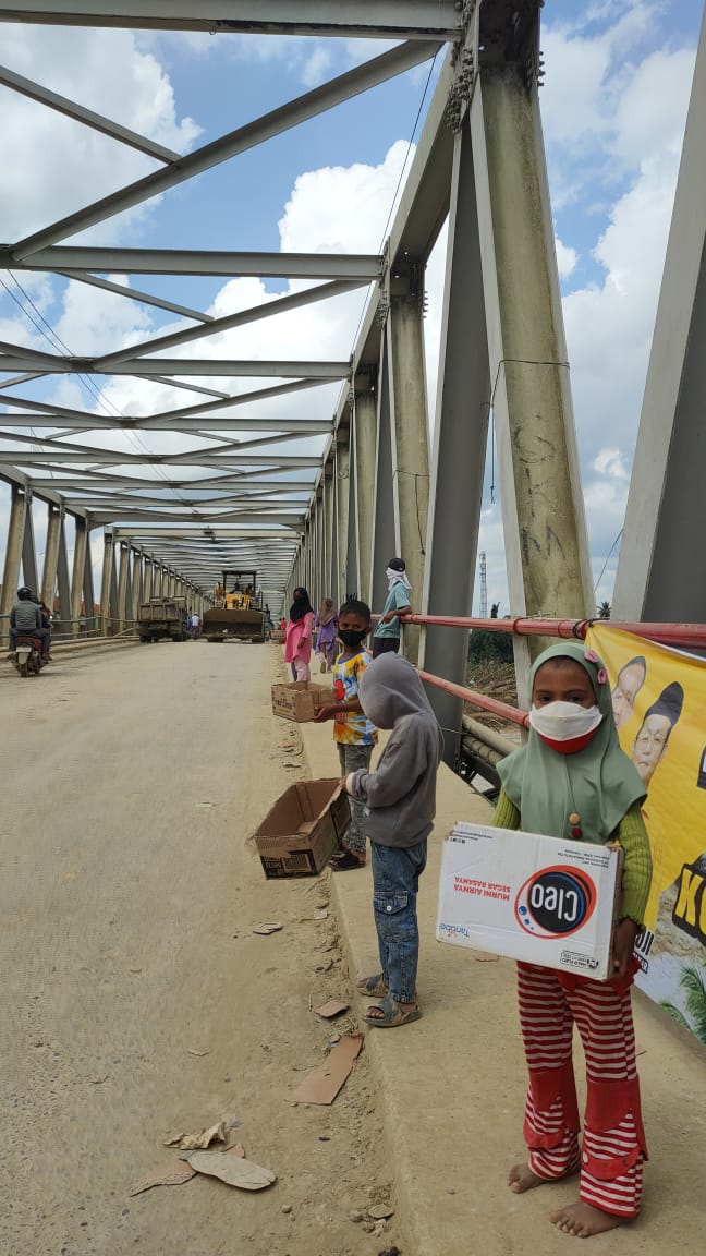 Pengemis kecil berdiri di Jembatan Kualasimpang sambil menadahkan tangan kepada pengendara yang melintas